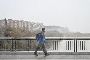 Archivo - Una persona camina por la calle bajo la nieve, a 19 de enero de 2024, en Zaragoza, Aragón (España). La Aemet ha activado la alerta naranja en la provincia de Zaragoza por una acumulación 