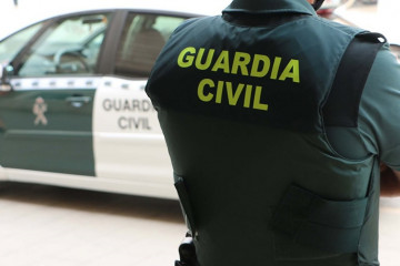 Archivo - Un agente de la Guardia Civil, de espaldas, junto a un vehículo oficial.