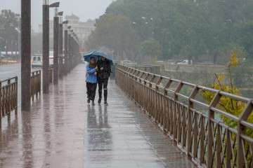 Archivo - Peatones bajo la lluvia  por el Puente de los Remedios  en Sevilla a 22 de noviembre del 2019