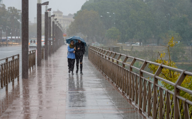 Archivo - Peatones bajo la lluvia  por el Puente de los Remedios  en Sevilla a 22 de noviembre del 2019