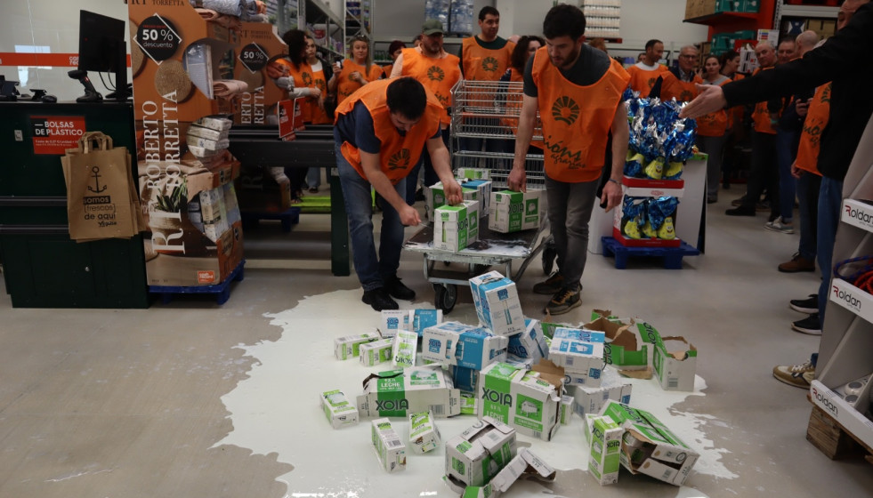 Varios miembros de Unións Agrarias derraman leche en el centro de Cash Galicia
