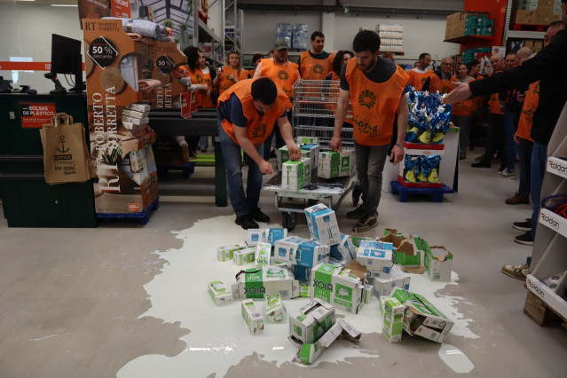 Varios miembros de Unións Agrarias derraman leche en el centro de Cash Galicia