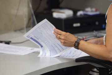 Archivo - Una empleada hojea varias hojas en su puesto de trabajo de la Oficina de Hacienda de la Calle de Guzmán el Bueno, a 27 de julio de 2021, en Madrid, (España). El Gobierno prevé aprobar est