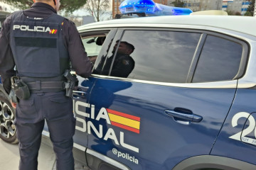 Un agente y un coche de la Policía Nacional.