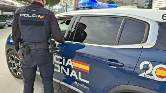 Un agente y un coche de la Policía Nacional.