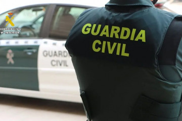 Archivo - Un agente de la Guardia Civil junto a un vehículo oficial.