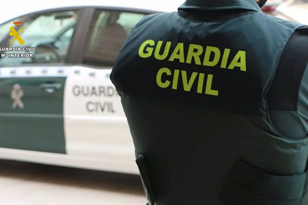Archivo - Un agente de la Guardia Civil junto a un vehículo oficial.