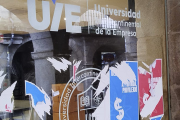 Restos de carteles en la vidriera de la sede de la UIE en Santiago de Compostela