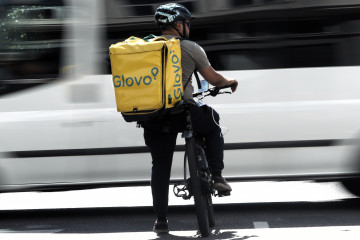 Archivo - Un rider de la empresa de reparto de comida a domicilio Glovo, pasea por una calle de Madrid con su bicicleta