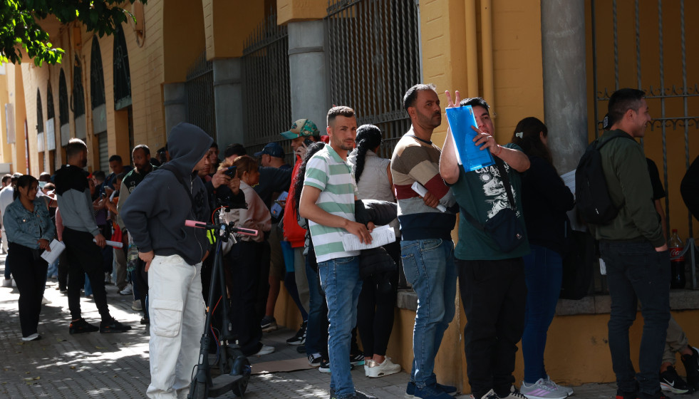 Personas migrantes hacen cola para la tramitación de su regularización administrativa en Sevilla.