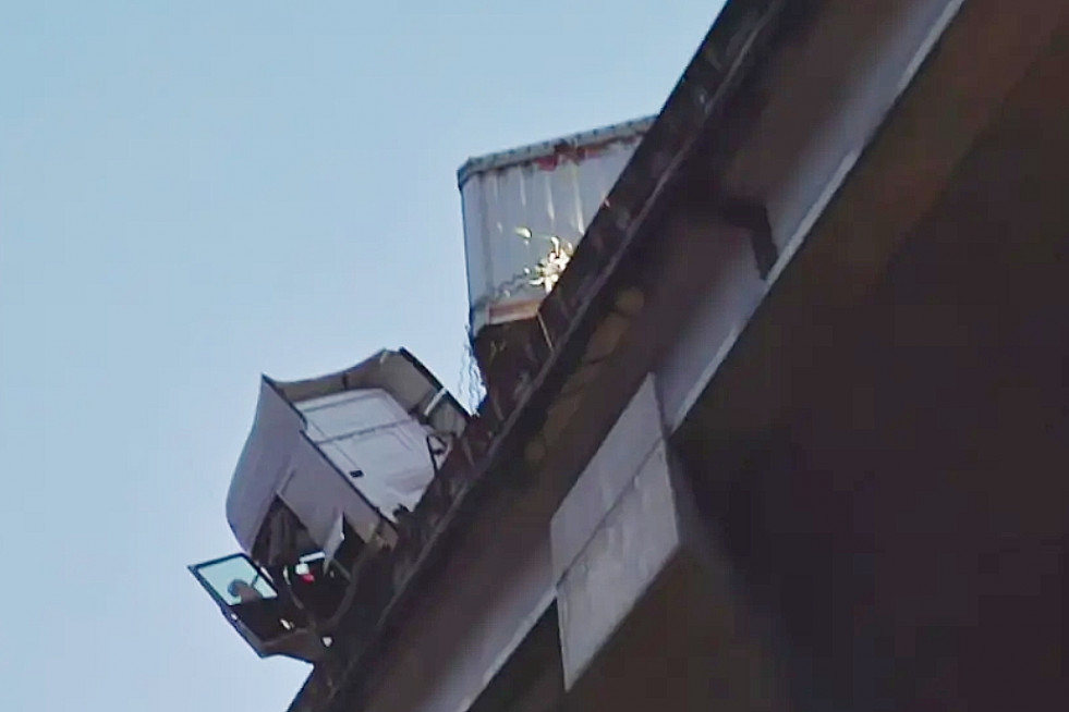 Cabina del camión con la puerta abierta colgando sobre el viaducto